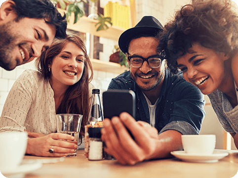 Group of friends seated at table looking at phone
